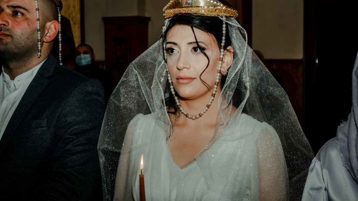 Bride and groom in a traditional wedding ceremony with cultural crowns and attire.